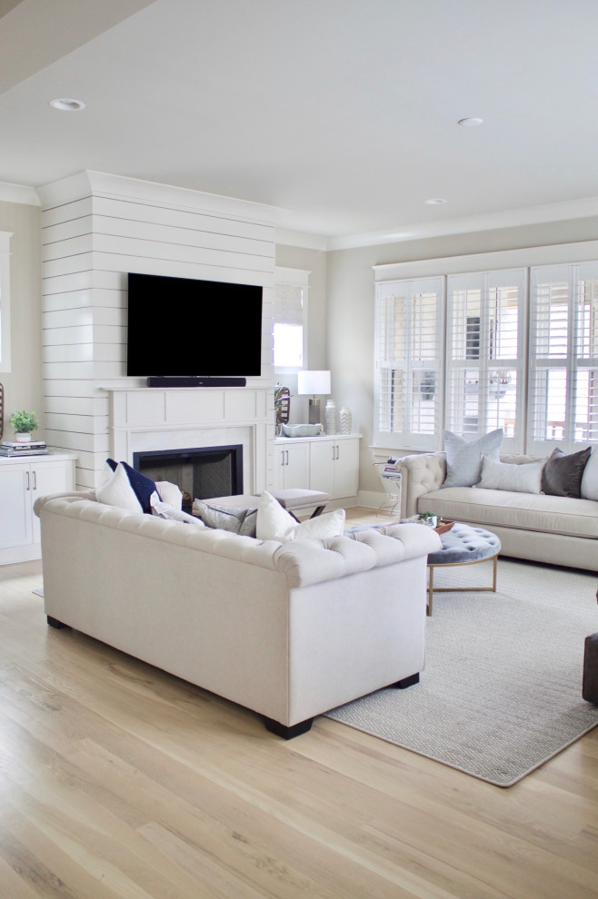 Example of a large trendy open concept light wood floor and beige floor living room design in Nashville with beige walls, a standard fireplace, a shiplap fireplace and a wall-mounted tv