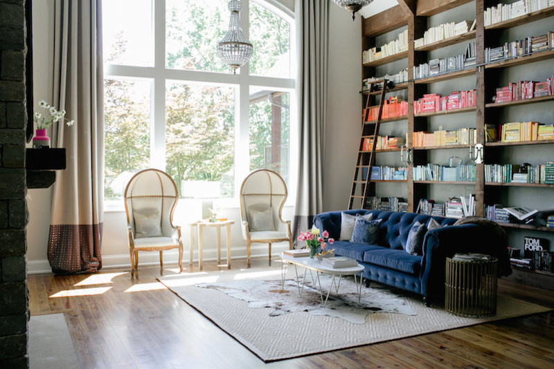 Foto de biblioteca en casa abierta actual grande con paredes grises, suelo de madera en tonos medios y marco de chimenea de piedra