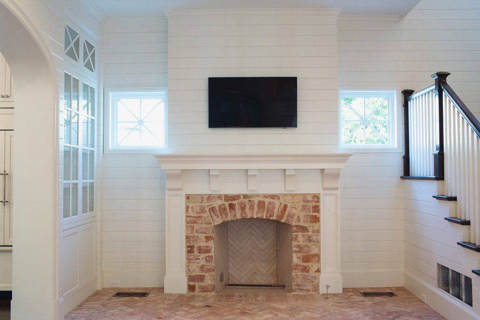 ダラスにある中くらいなトラディショナルスタイルのおしゃれなリビング (白い壁、レンガの床、標準型暖炉、レンガの暖炉まわり、壁掛け型テレビ、ピンクの床) の写真