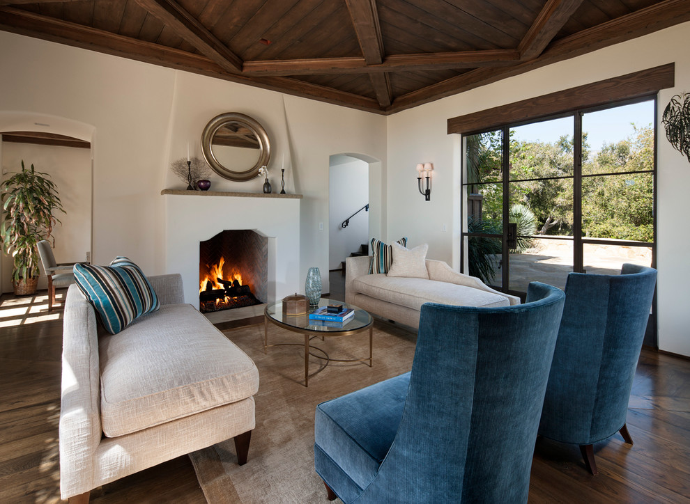Fernseherloses Mediterranes Wohnzimmer mit weißer Wandfarbe, dunklem Holzboden und Kamin in Santa Barbara