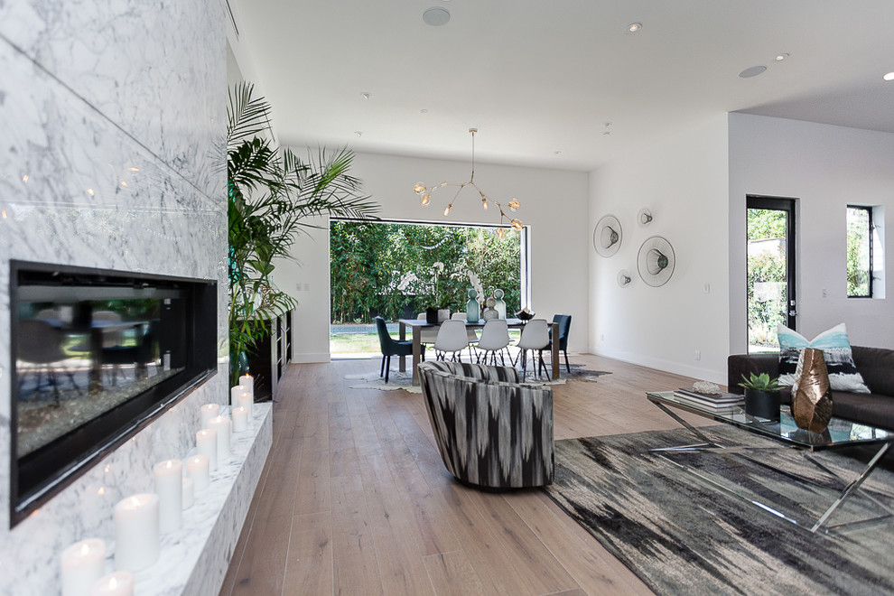 Modelo de salón para visitas abierto minimalista grande sin televisor con paredes blancas, suelo vinílico, chimenea lineal y marco de chimenea de piedra