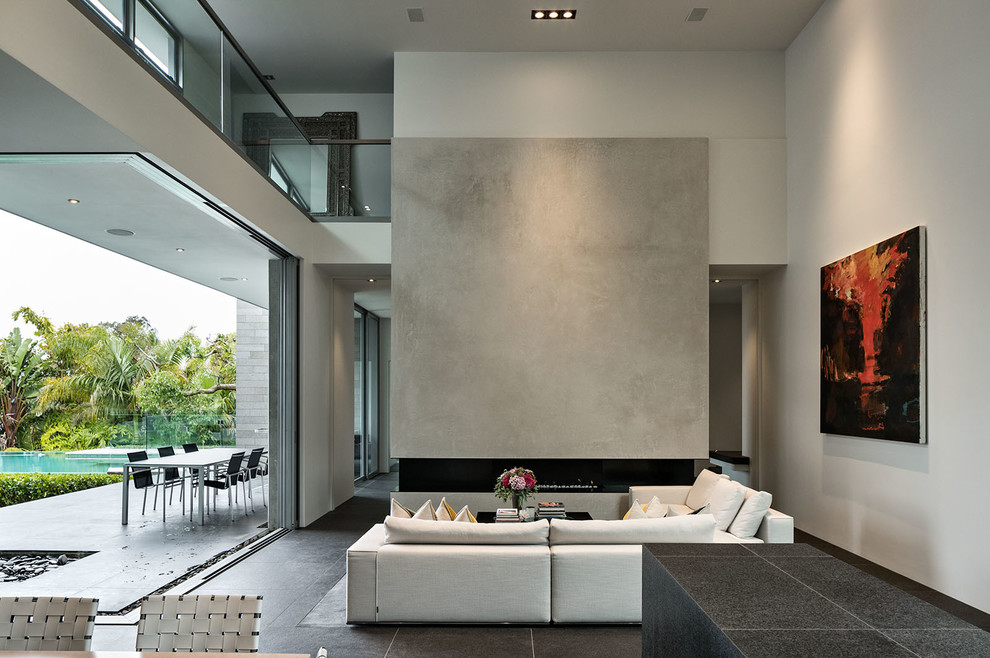Diseño de salón minimalista con paredes blancas, chimenea lineal, marco de chimenea de hormigón, suelo negro y suelo de baldosas de cerámica