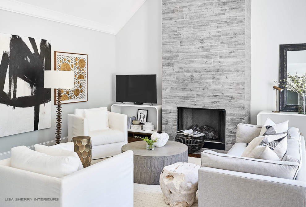 Cette image montre un salon minimaliste de taille moyenne et ouvert avec un mur gris, parquet foncé, une cheminée standard, un manteau de cheminée en carrelage, un téléviseur indépendant et un sol marron.
