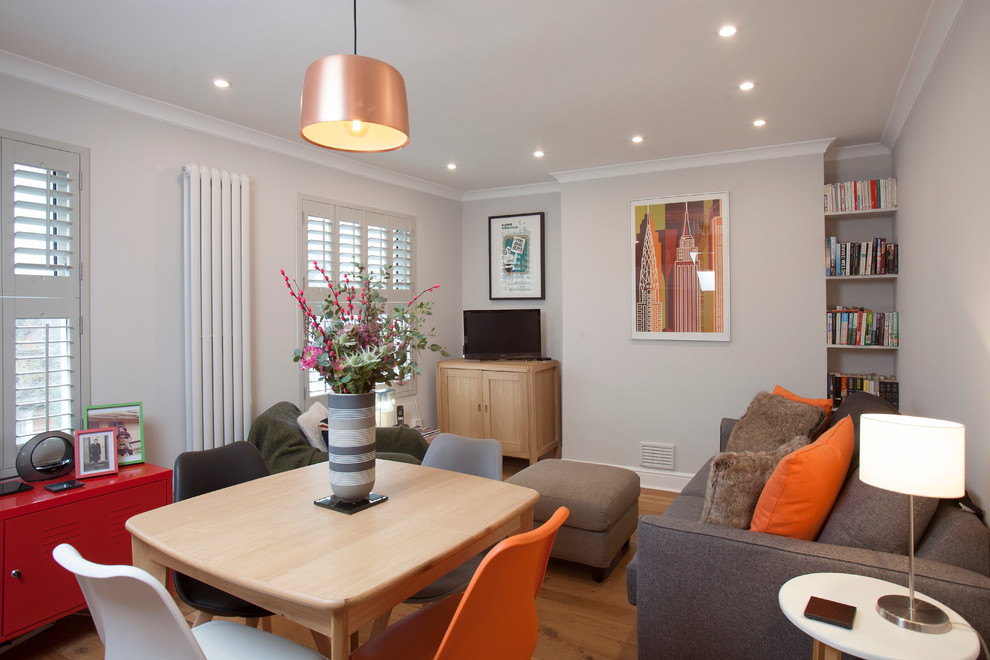 Example of a small trendy open concept light wood floor living room design in London with gray walls and a tv stand