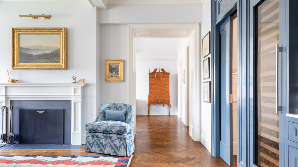 Foto di un piccolo soggiorno classico con pareti grigie, pavimento in legno massello medio, camino classico, cornice del camino in legno e pavimento marrone