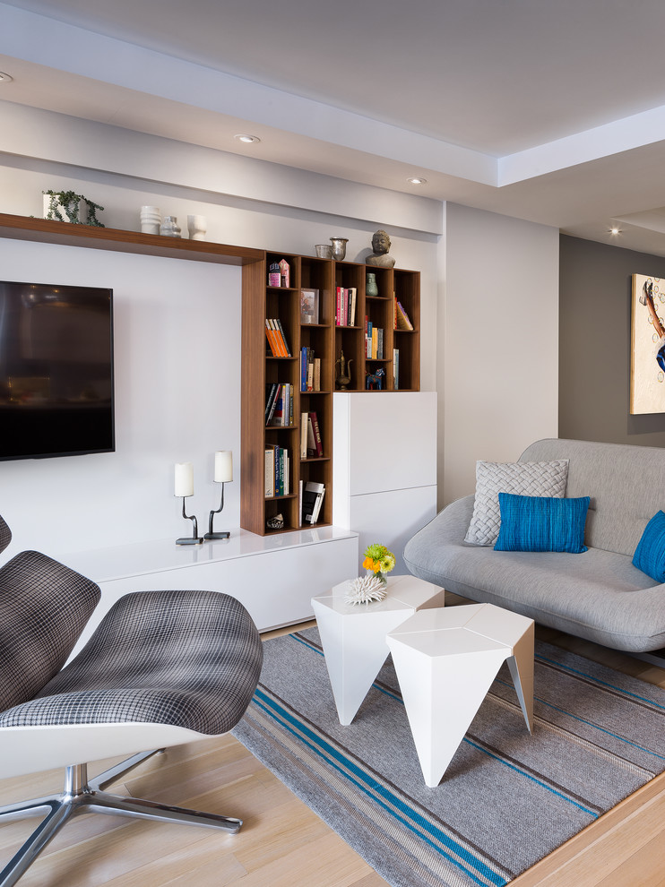 Foto di un soggiorno design aperto con pareti grigie, parquet chiaro e TV a parete