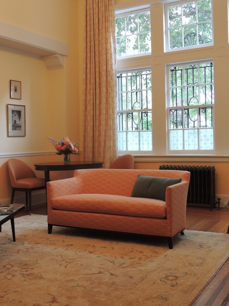 Kleines, Fernseherloses, Offenes Klassisches Wohnzimmer mit gelber Wandfarbe, braunem Holzboden, Kamin und Kaminumrandung aus Stein in New York