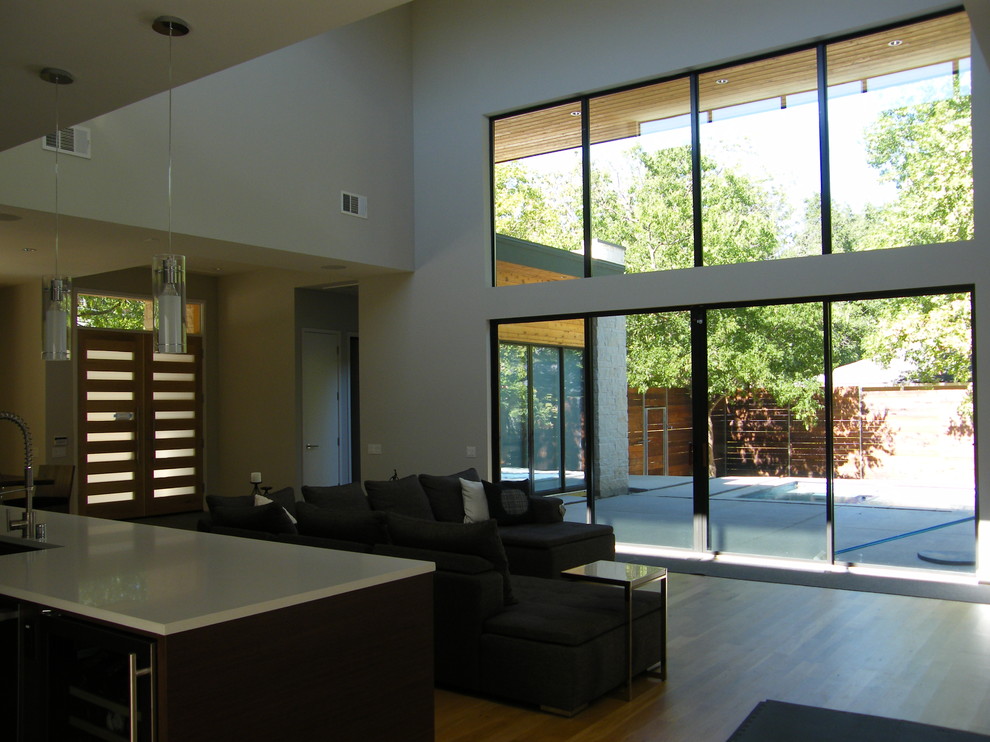 Aménagement d'un grand salon moderne ouvert avec un mur blanc, parquet clair et un sol marron.