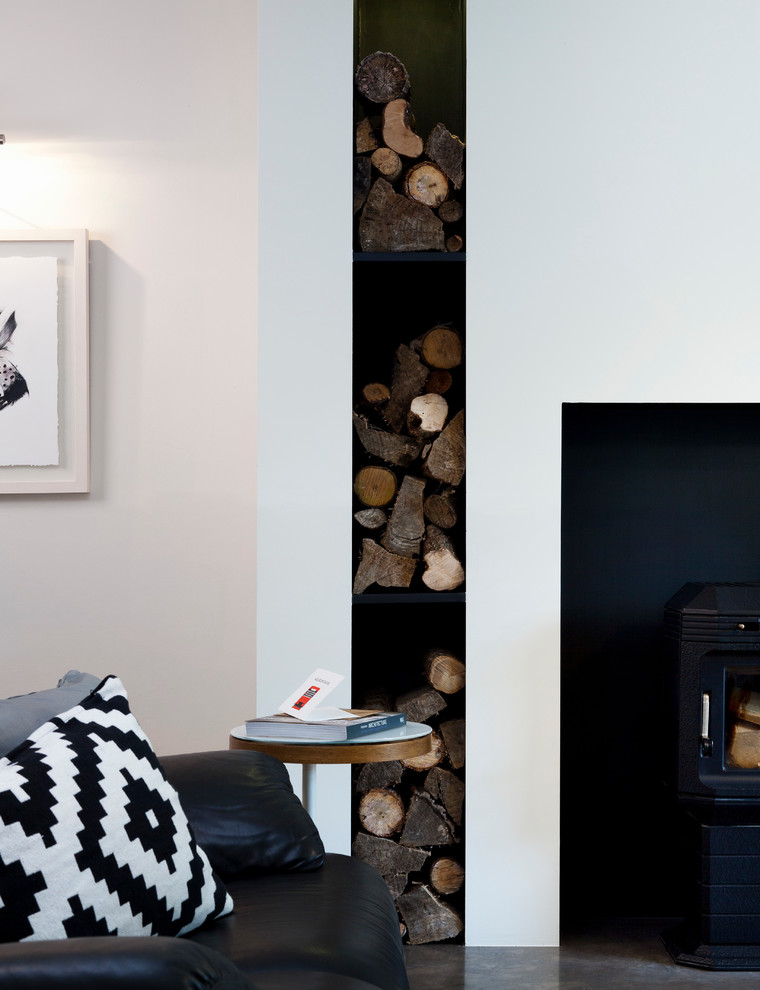 Cette image montre un salon minimaliste de taille moyenne et fermé avec un mur blanc, un poêle à bois et un téléviseur indépendant.