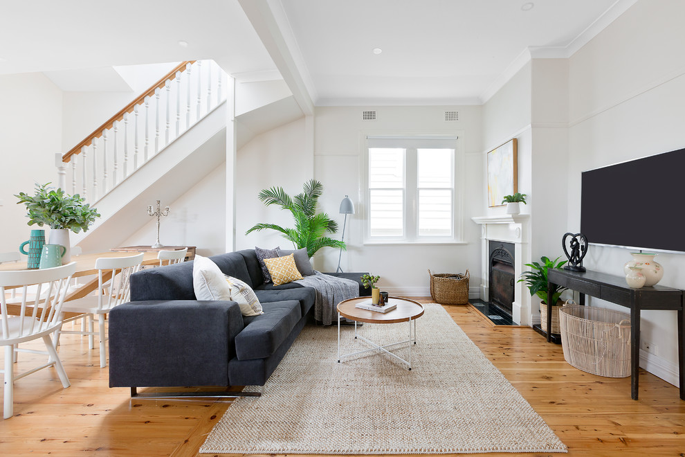 Esempio di un soggiorno chic aperto con pareti bianche, pavimento in legno massello medio, camino classico, TV a parete e pavimento marrone