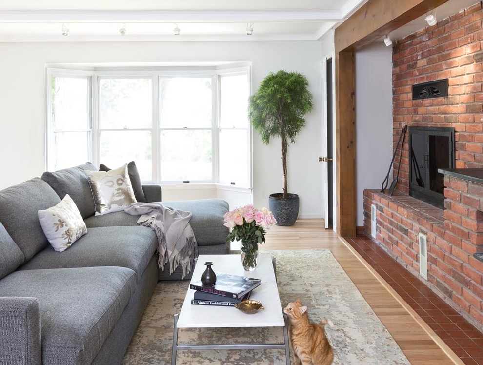 Living room - mid-sized transitional enclosed light wood floor living room idea in Detroit with white walls, a standard fireplace, a brick fireplace and a media wall