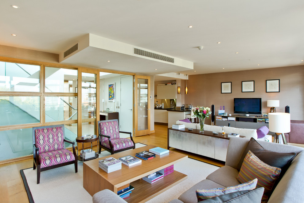Example of a trendy living room design in London with beige walls and a tv stand