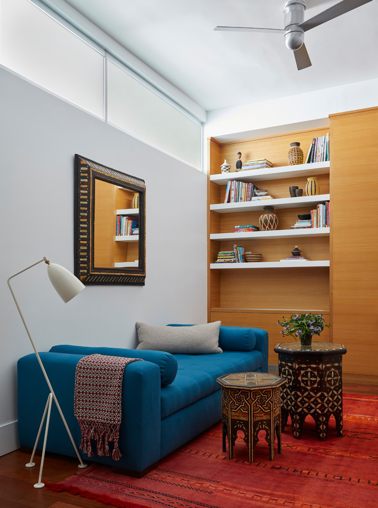 Стильный дизайн: гостиная комната среднего размера в современном стиле с белыми стенами, паркетным полом среднего тона, коричневым полом и синим диваном - последний тренд