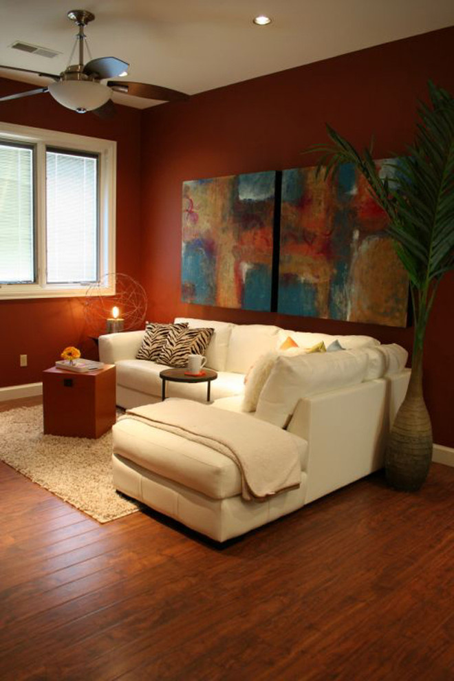 Idée de décoration pour un petit salon design ouvert avec un mur orange et un sol en bois brun.