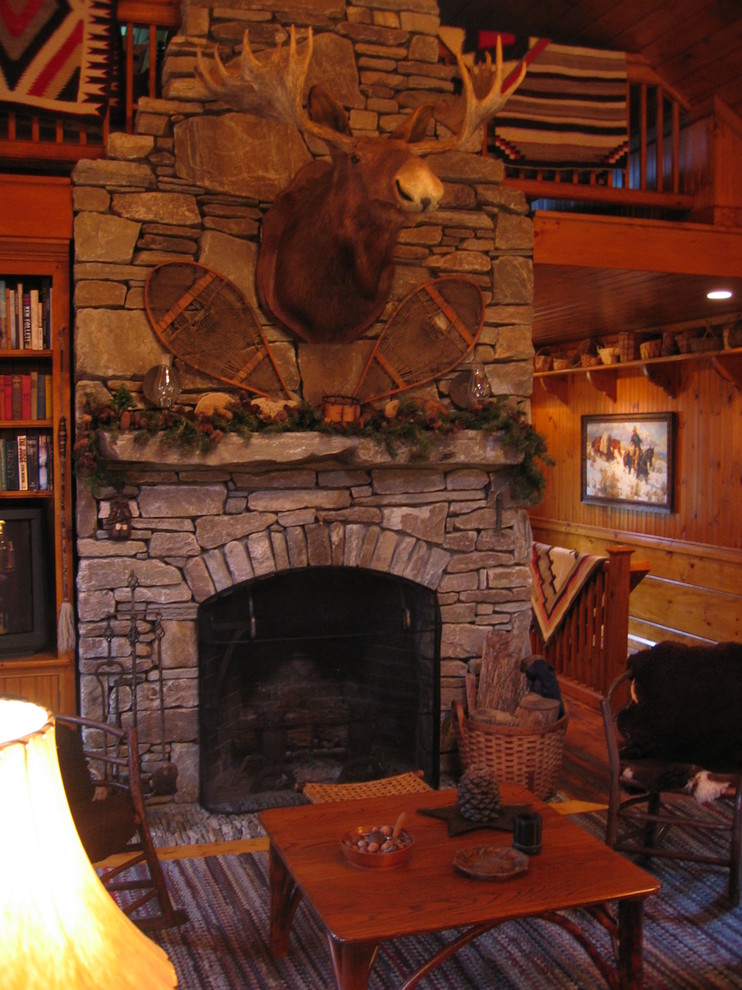 Small rustic mezzanine living room in Boston with a standard fireplace, a stone fireplace surround, brown walls, medium hardwood flooring and a concealed tv.