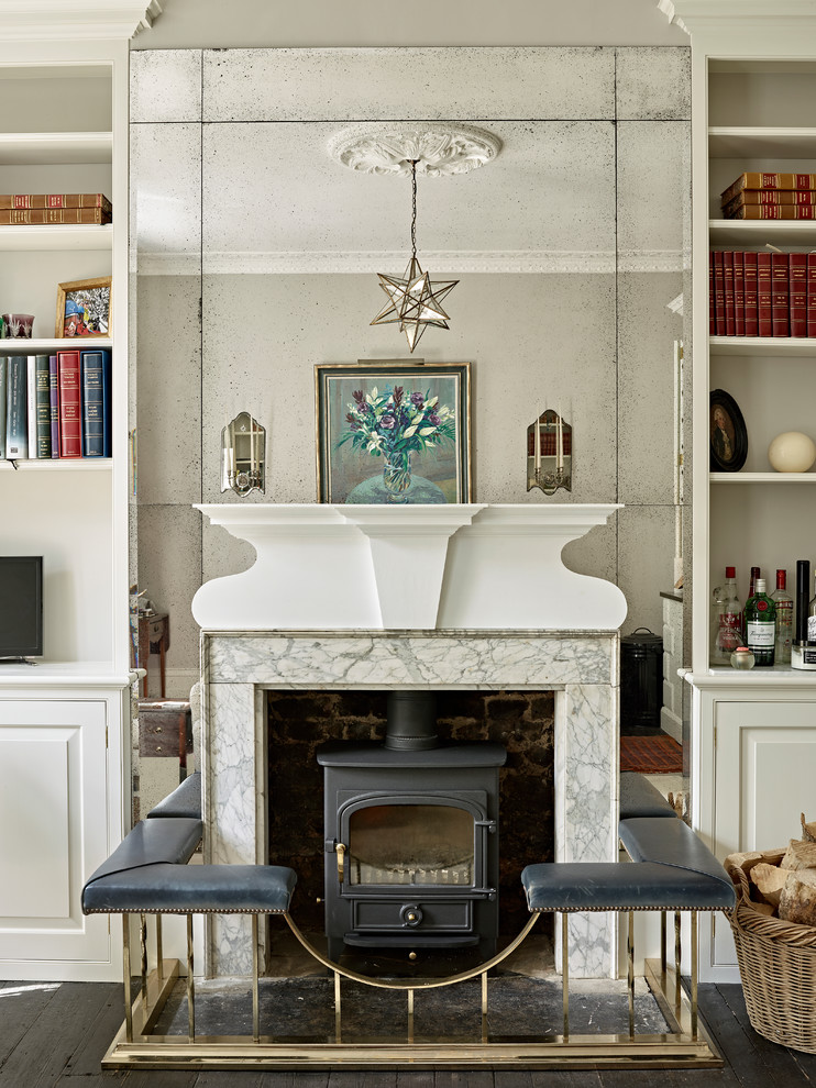 Klassisches Wohnzimmer mit beiger Wandfarbe, dunklem Holzboden, Kaminofen, Kaminumrandung aus Stein und schwarzem Boden in London