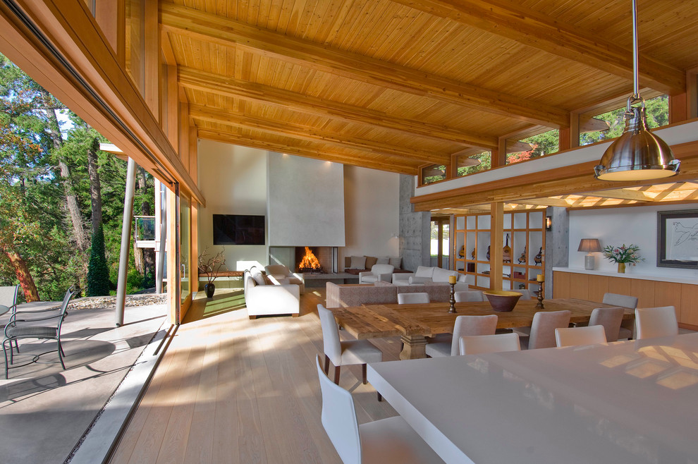 Esempio di un grande soggiorno design aperto con parquet chiaro e camino classico