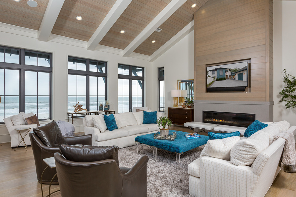 Medium sized beach style formal enclosed living room in Miami with white walls, light hardwood flooring, a standard fireplace, a concrete fireplace surround, a wall mounted tv and feature lighting.