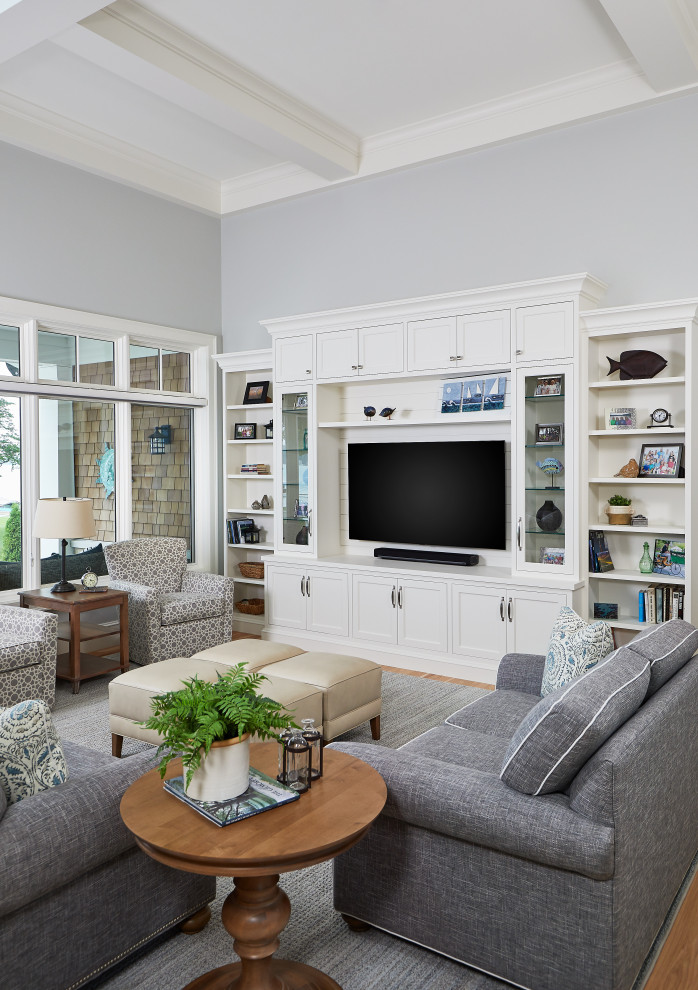 Design ideas for a traditional open plan living room in Grand Rapids with blue walls, medium hardwood flooring, a two-sided fireplace, a stone fireplace surround, a built-in media unit and a coffered ceiling.