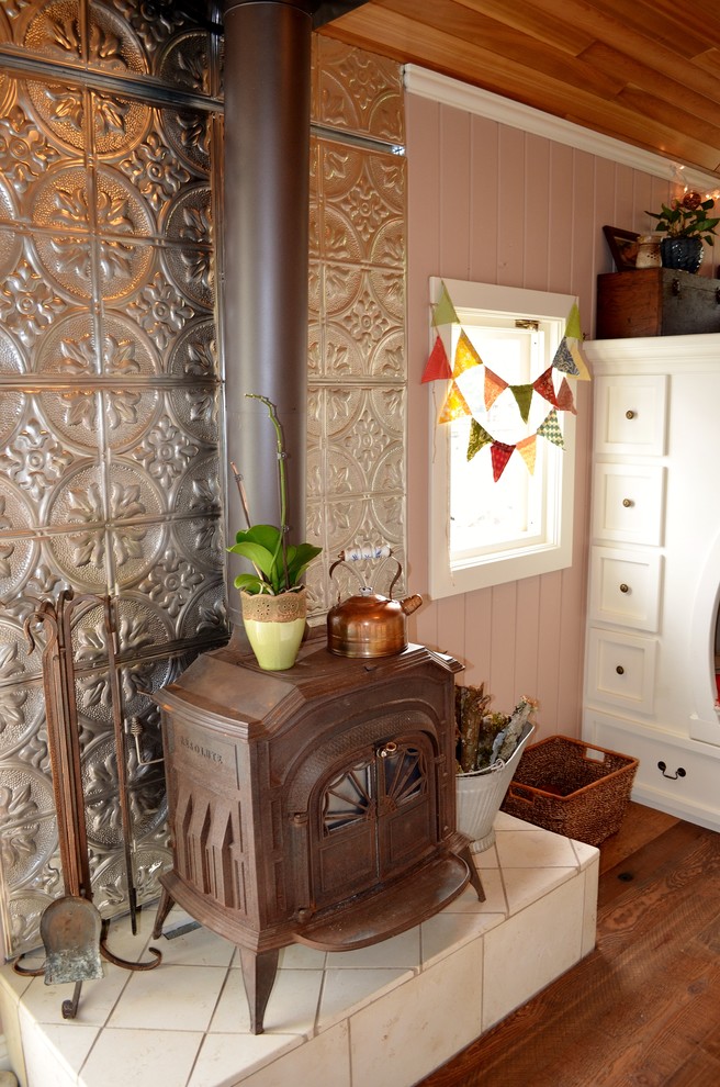 Foto de salón abierto de estilo americano pequeño sin televisor con paredes beige, suelo de madera en tonos medios, estufa de leña y marco de chimenea de metal