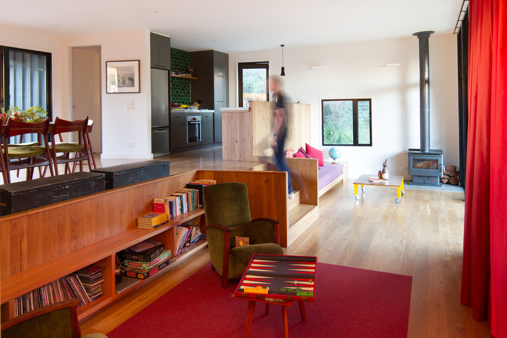 Стильный дизайн: открытая гостиная комната в современном стиле с светлым паркетным полом, печью-буржуйкой и белыми стенами - последний тренд