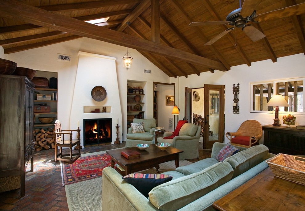 Modelo de salón para visitas abierto campestre grande con paredes blancas, suelo de ladrillo, todas las chimeneas y marco de chimenea de yeso