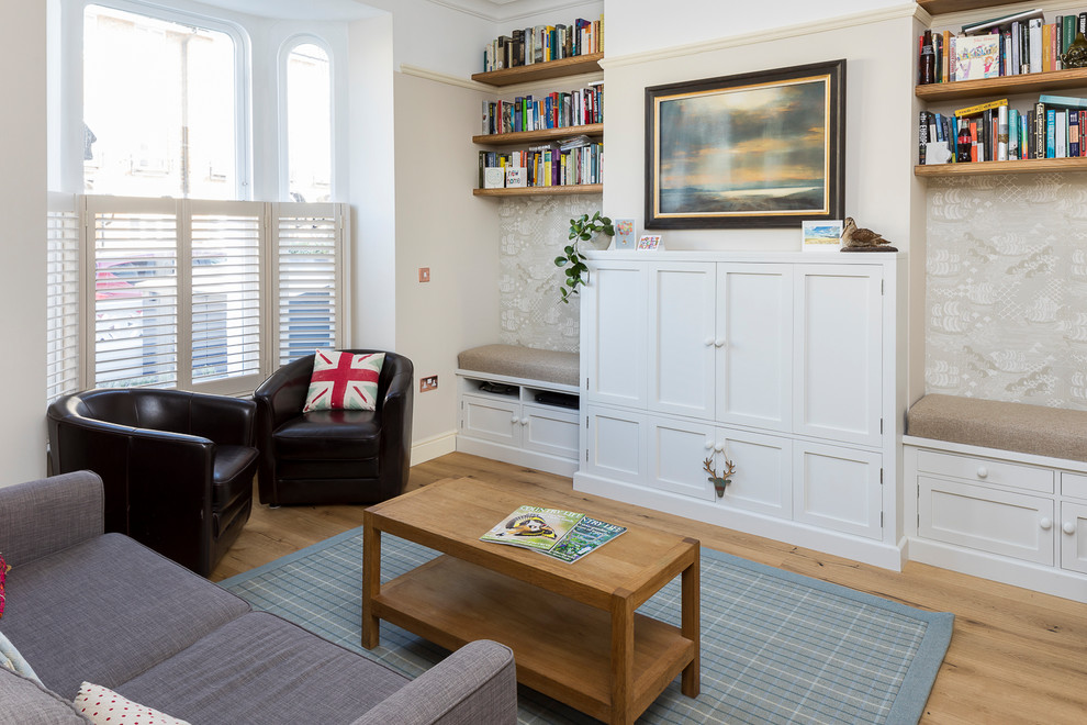 Imagen de salón cerrado tradicional renovado de tamaño medio con paredes beige, suelo de madera clara, televisor retractable y suelo marrón