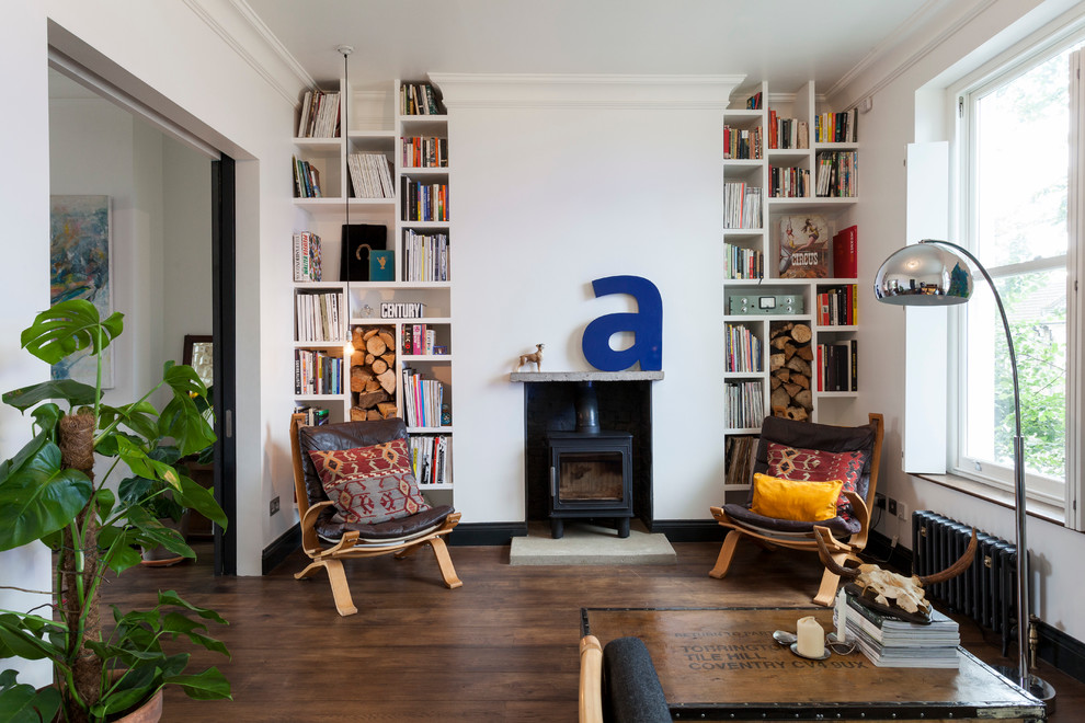 Immagine di un soggiorno scandinavo chiuso con libreria, pareti bianche, pavimento in legno massello medio, stufa a legna e cornice del camino in metallo