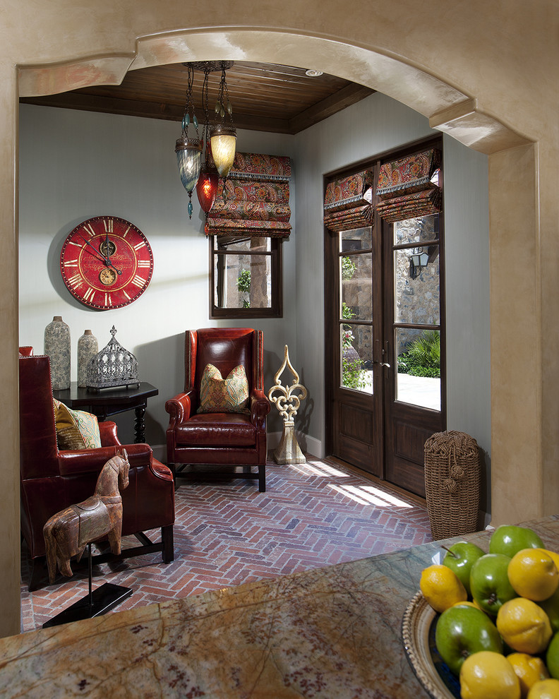 Cette image montre un petit salon méditerranéen avec un sol en brique, un mur gris et un sol rouge.
