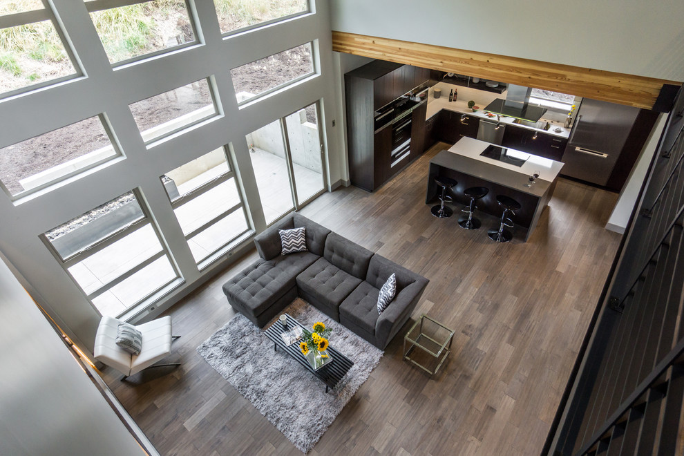 Foto di un grande soggiorno minimalista aperto con pareti grigie, pavimento in legno massello medio e TV a parete