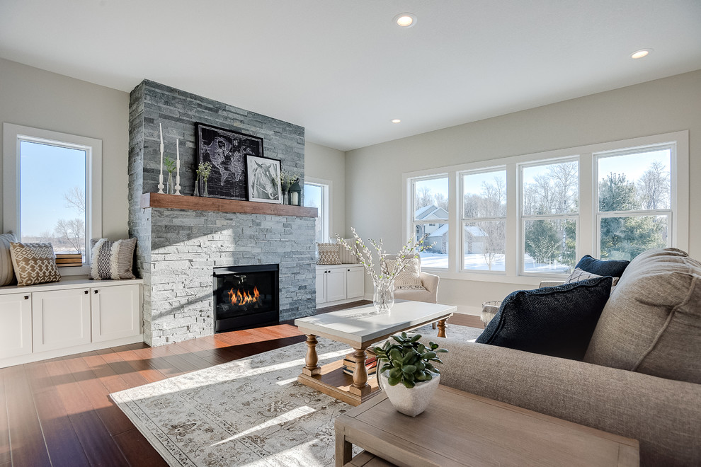 Example of a mid-sized transitional formal and open concept medium tone wood floor and brown floor living room design in Minneapolis with gray walls, a standard fireplace, a stone fireplace and no tv