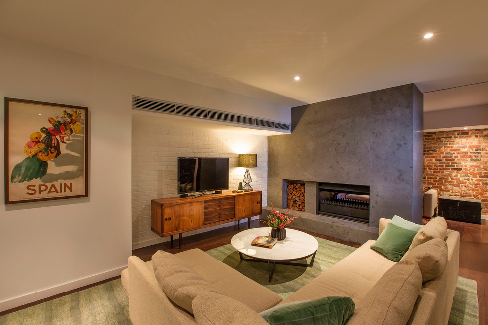 На фото: изолированная гостиная комната среднего размера в современном стиле с с книжными шкафами и полками, белыми стенами, темным паркетным полом, двусторонним камином, фасадом камина из бетона и отдельно стоящим телевизором