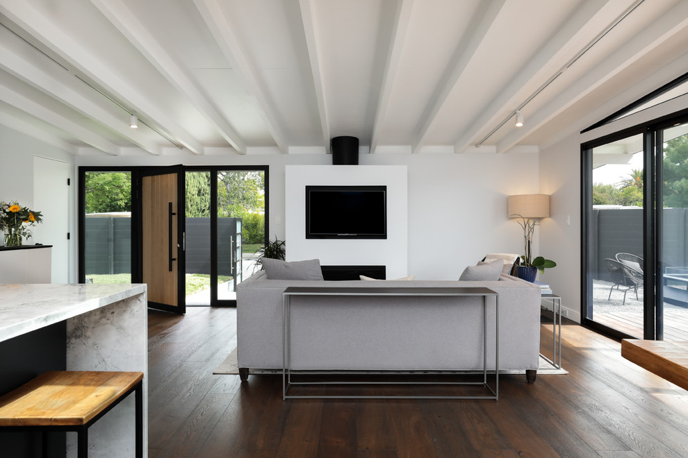 Diseño de salón abierto minimalista de tamaño medio con paredes blancas, suelo de madera oscura, chimenea lineal, marco de chimenea de metal y suelo marrón