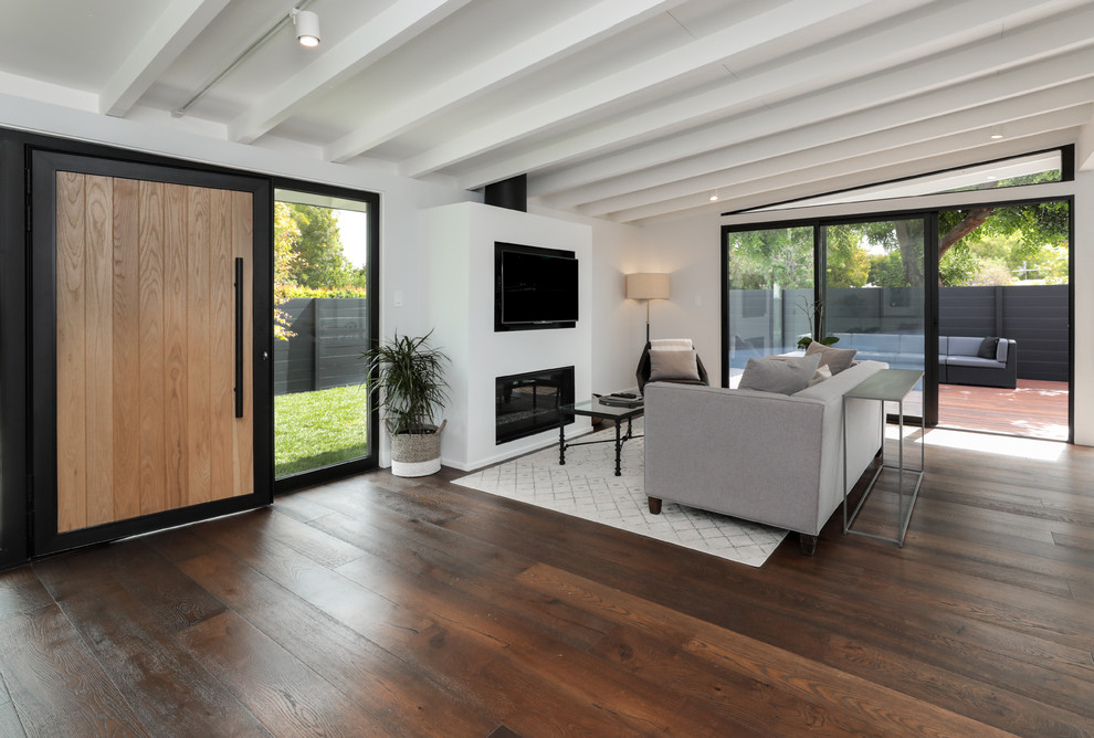 Diseño de salón abierto moderno de tamaño medio con paredes blancas, suelo de madera oscura, chimenea lineal, marco de chimenea de metal y suelo marrón