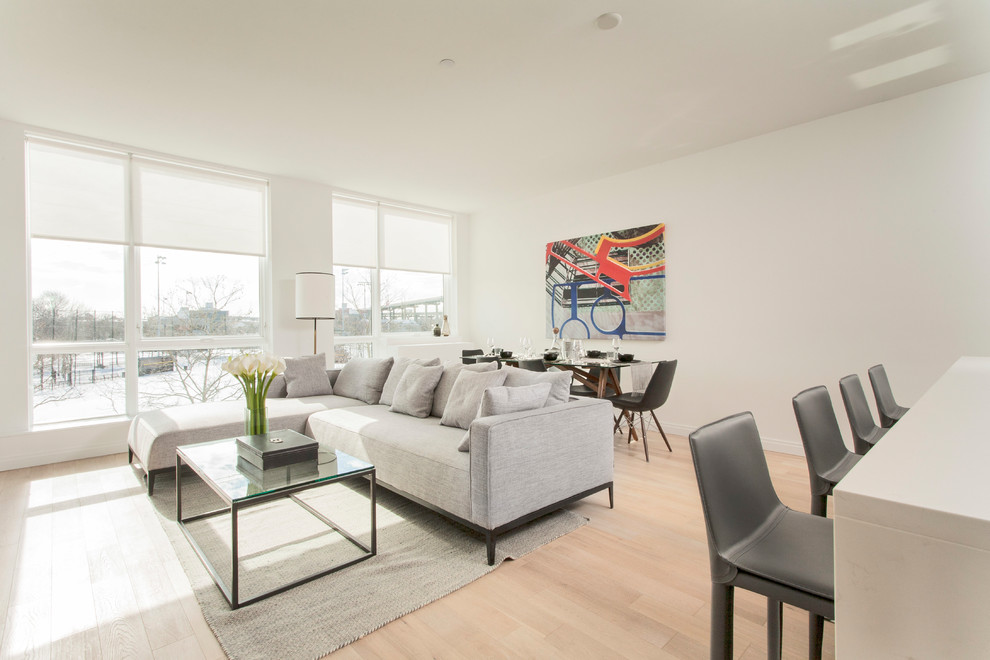 Medium sized modern open plan living room in New York with white walls, light hardwood flooring and beige floors.