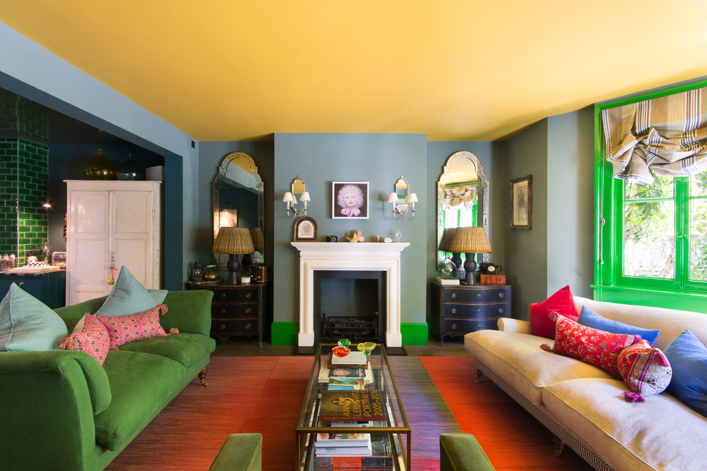 This is an example of a medium sized bohemian enclosed living room in London with green walls, carpet, a standard fireplace, a stone fireplace surround and beige floors.