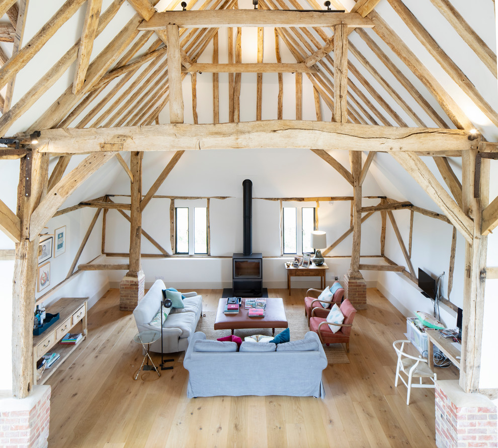 Esempio di un grande soggiorno minimal aperto con parquet chiaro, stufa a legna e pavimento marrone