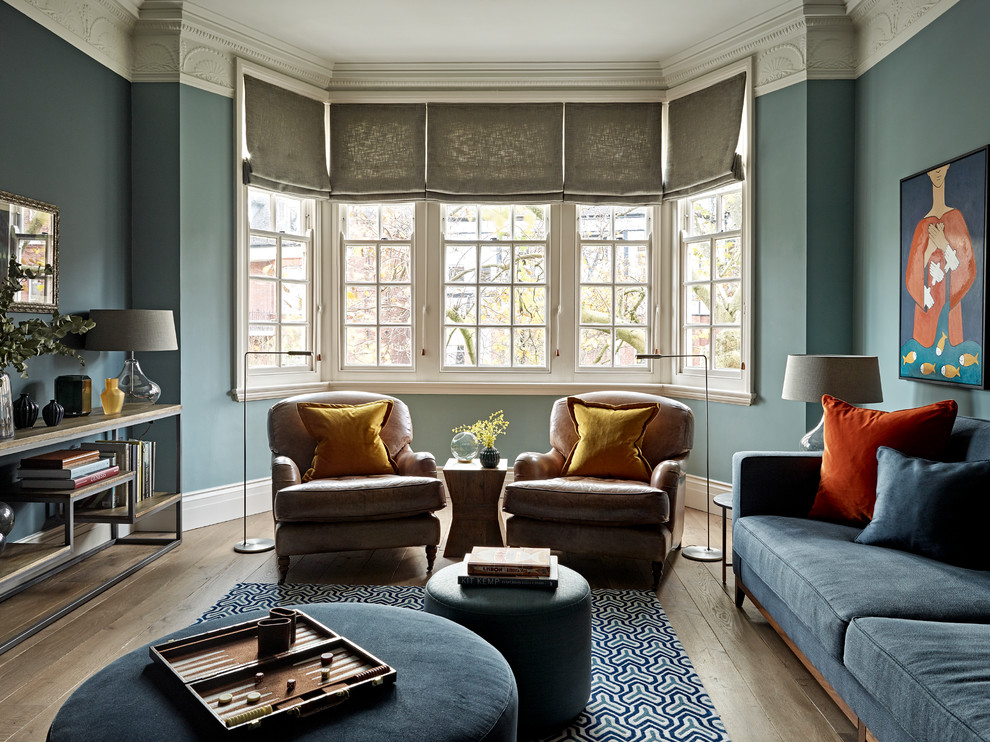 ロンドンにあるトランジショナルスタイルのおしゃれなリビング (青い壁、淡色無垢フローリング、ベージュの床、青いソファ) の写真