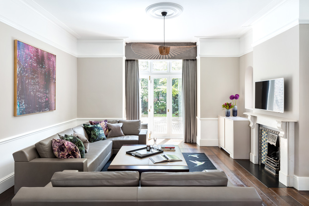Mittelgroßes, Abgetrenntes Klassisches Wohnzimmer mit grauer Wandfarbe, dunklem Holzboden, Kamin, Kaminumrandung aus Stein, TV-Wand und braunem Boden in London