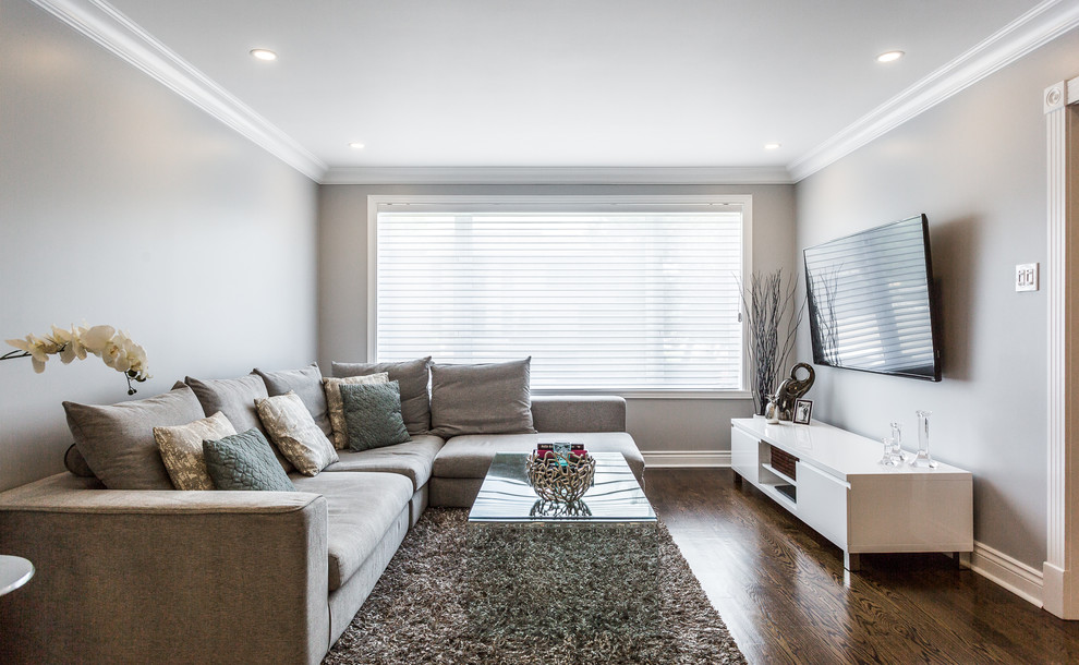 Стильный дизайн: изолированная гостиная комната среднего размера в стиле неоклассика (современная классика) с серыми стенами, темным паркетным полом, телевизором на стене и коричневым полом - последний тренд