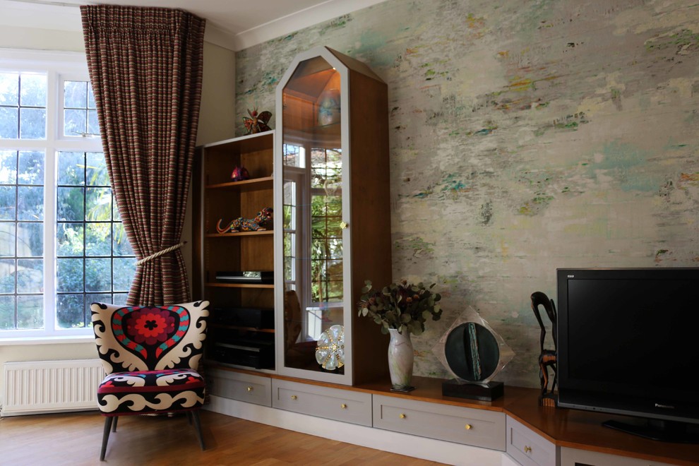 Mittelgroßes, Abgetrenntes Stilmix Wohnzimmer mit bunten Wänden, braunem Holzboden und freistehendem TV in Sonstige