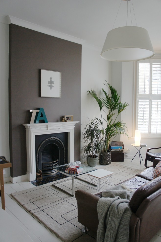 Photo of a small bohemian formal enclosed living room in London with white walls, light hardwood flooring, a standard fireplace, a metal fireplace surround and no tv.