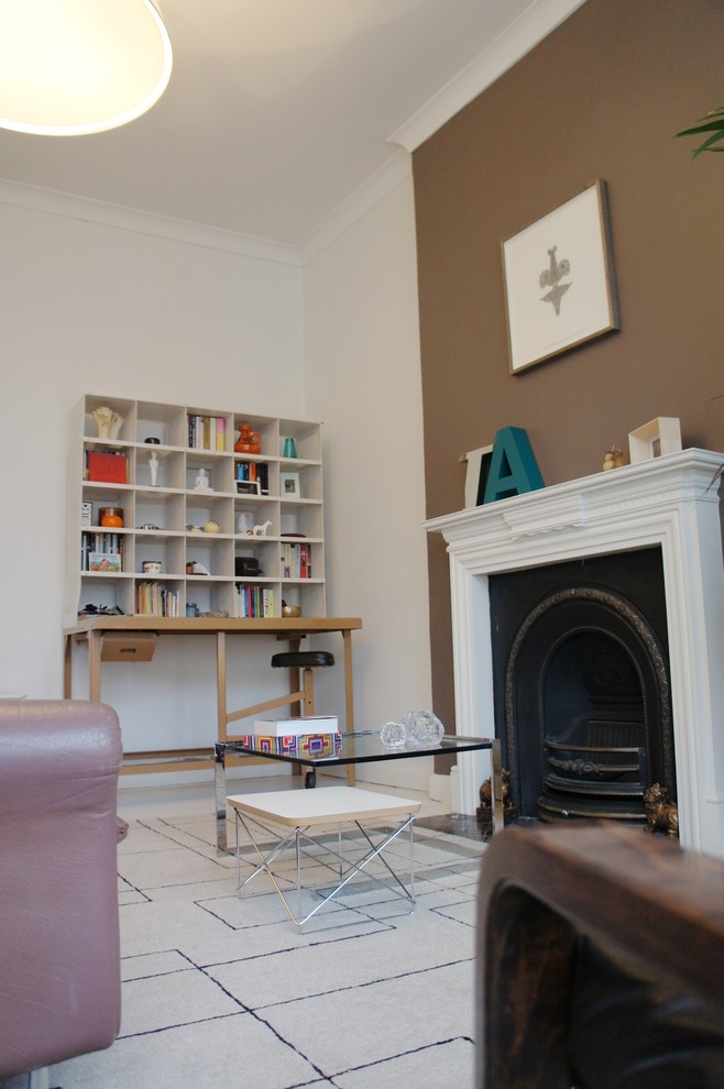 Photo of a small eclectic formal enclosed living room in London with white walls, light hardwood flooring, a standard fireplace, a metal fireplace surround and no tv.