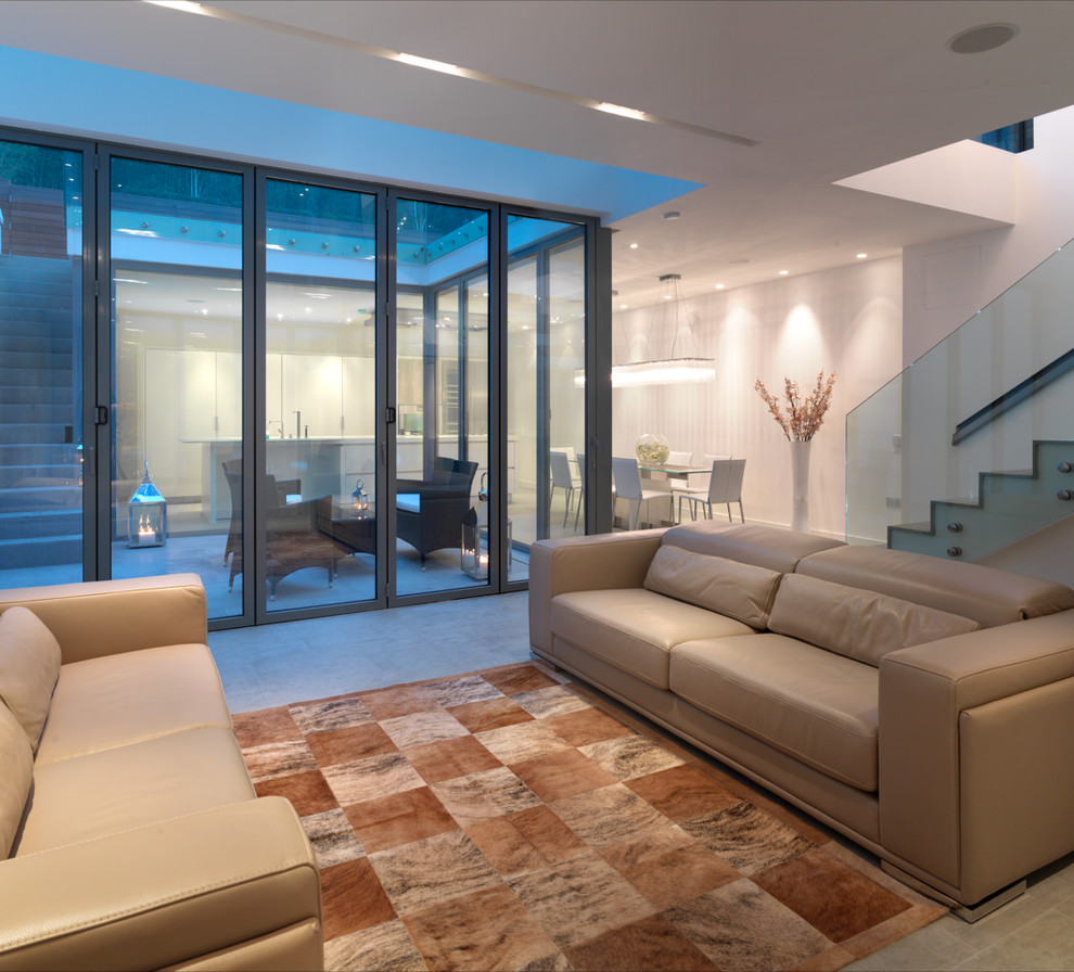 Diseño de salón abierto contemporáneo grande con paredes blancas, suelo de piedra caliza, televisor colgado en la pared y suelo gris