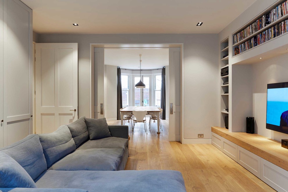 This is an example of a medium sized modern formal open plan living room in London with grey walls, light hardwood flooring, no fireplace, a stone fireplace surround and a freestanding tv.