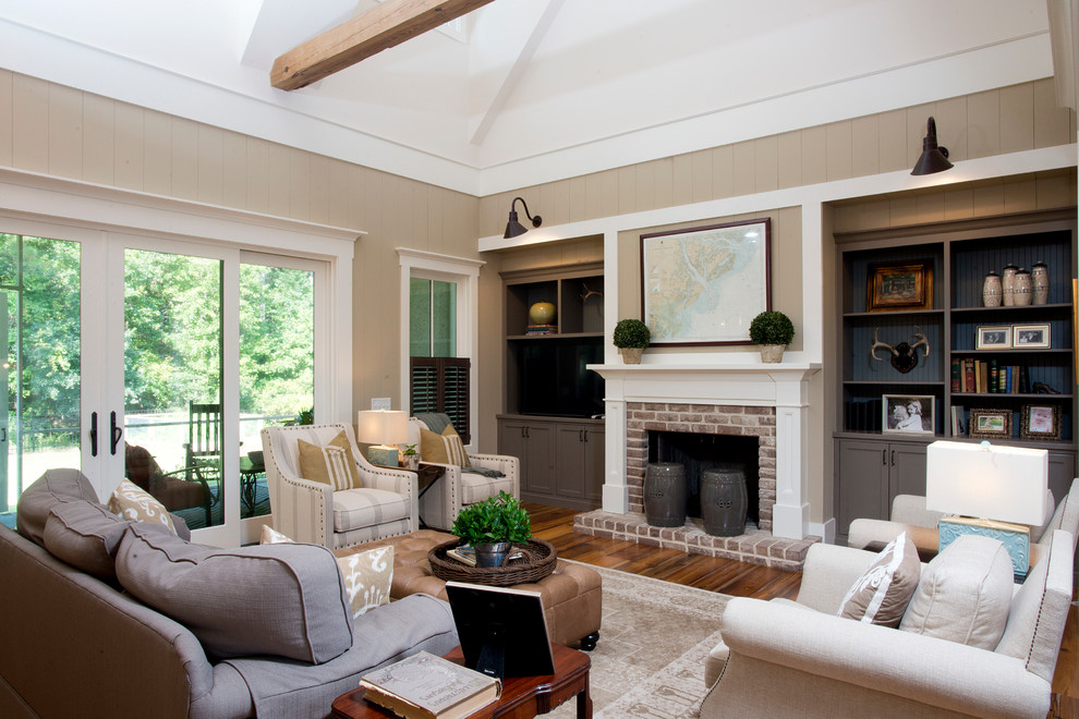 Repräsentatives, Abgetrenntes Country Wohnzimmer mit beiger Wandfarbe, braunem Holzboden, Kamin, Kaminumrandung aus Backstein und Multimediawand in Charleston