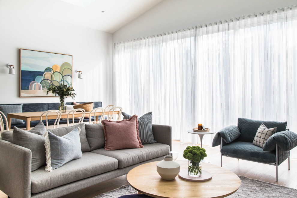 Offenes Modernes Wohnzimmer mit weißer Wandfarbe, hellem Holzboden und gewölbter Decke in Melbourne