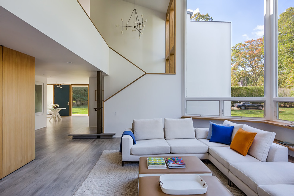 Esempio di un grande soggiorno minimal aperto con pareti bianche, pavimento in legno massello medio e pavimento grigio