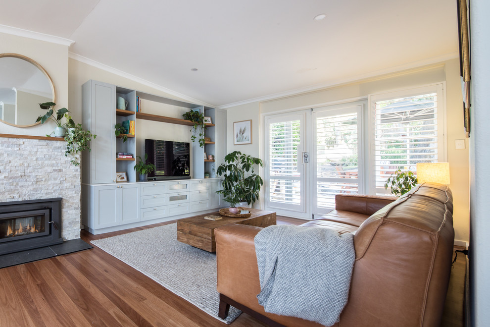 Mittelgroßes, Offenes Modernes Wohnzimmer mit weißer Wandfarbe, braunem Holzboden, Kamin, gefliester Kaminumrandung, Multimediawand und braunem Boden in Brisbane