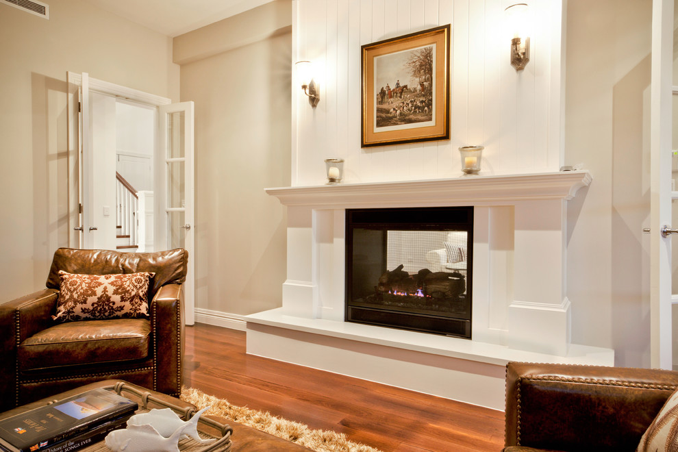 Источник вдохновения для домашнего уюта: открытая гостиная комната в морском стиле с белыми стенами, паркетным полом среднего тона, двусторонним камином и фасадом камина из дерева